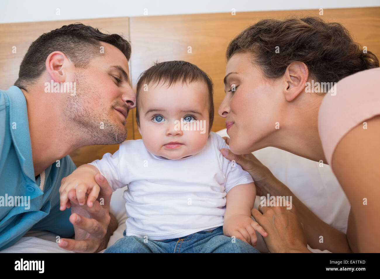 Parents kissing baby on cheek Stock Photo Alamy