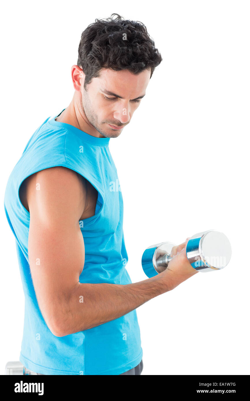 Serious young man exercising with dumbbell Stock Photo