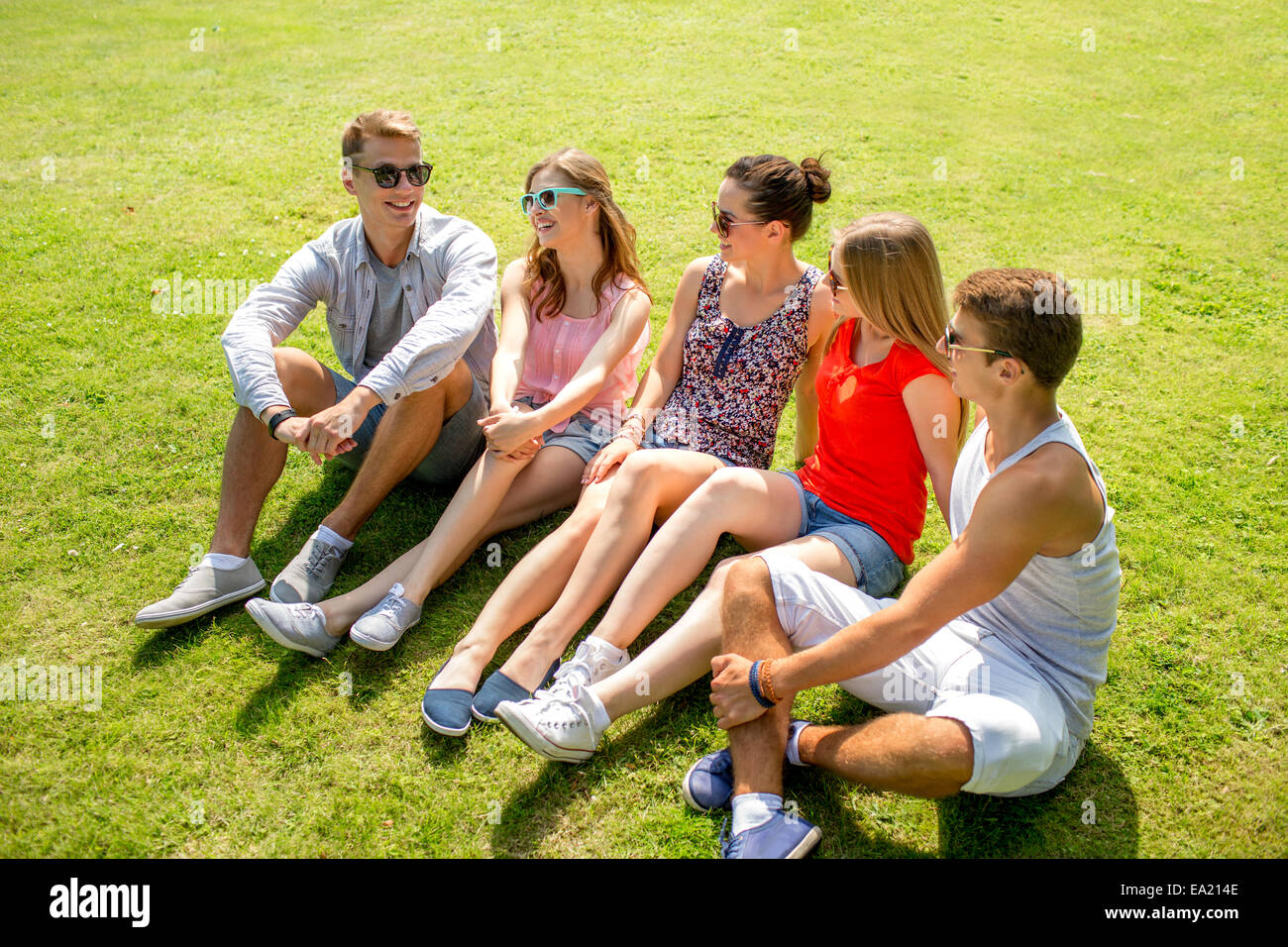 group of smiling friends outdoors sitting in park Stock Photo - Alamy
