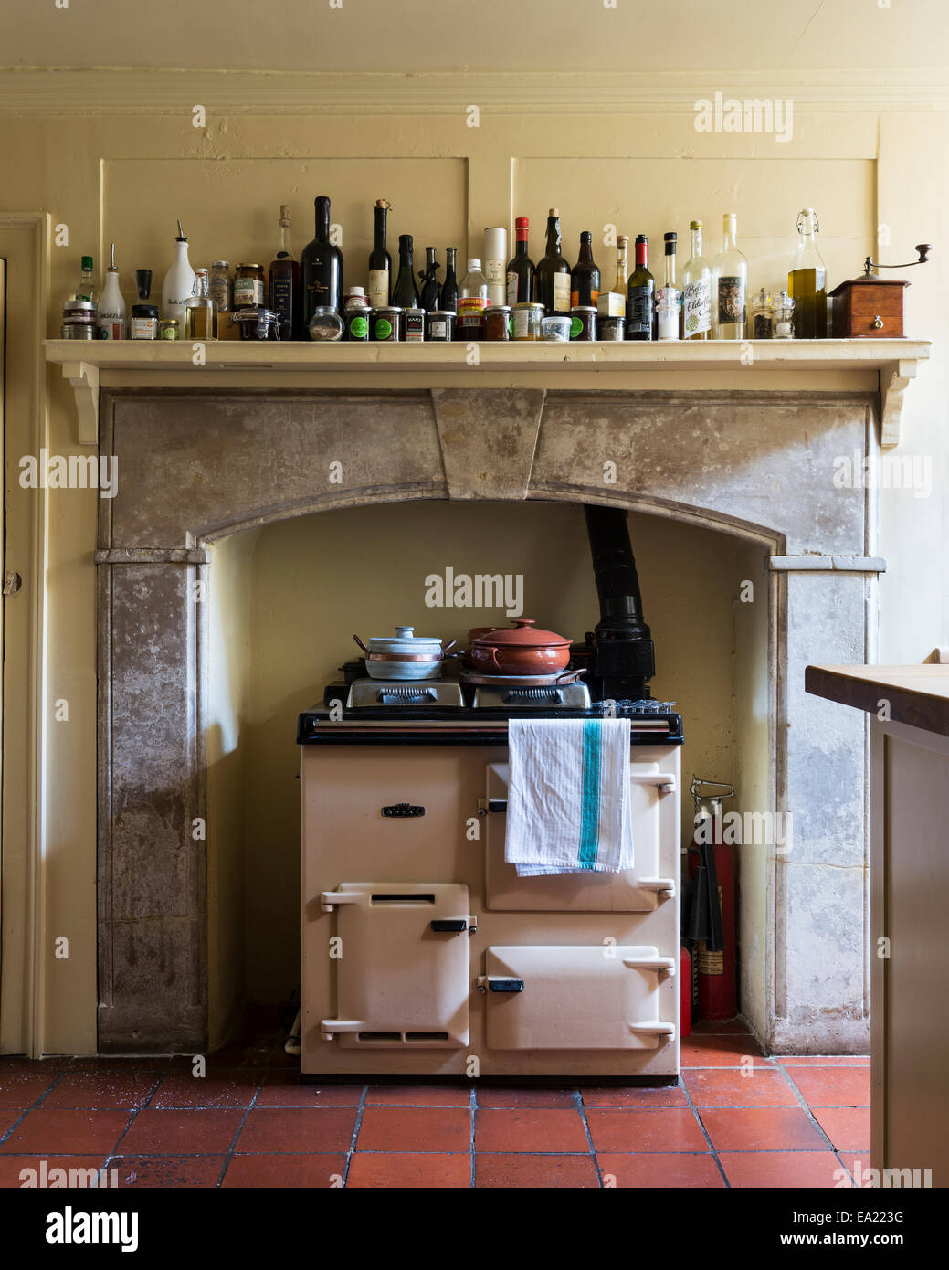 Rayburn cooker set back in large fireplace. Assorted bottles line the shelf above Stock Photo