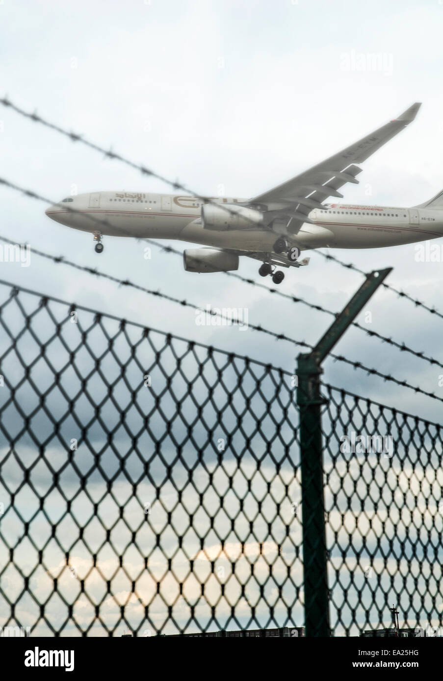 A plane from Etihad Airways flies over the fence from the grounds of the Frankfurt airport shortly before touchdown. Stock Photo