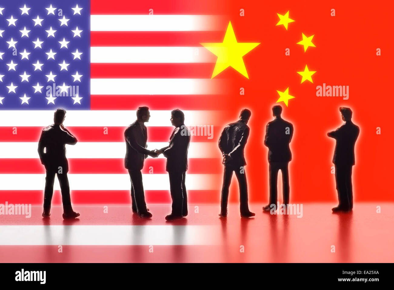 Model figures symbolizing politicians are facing the flags of China and the USA. Two of them shake hands. Stock Photo