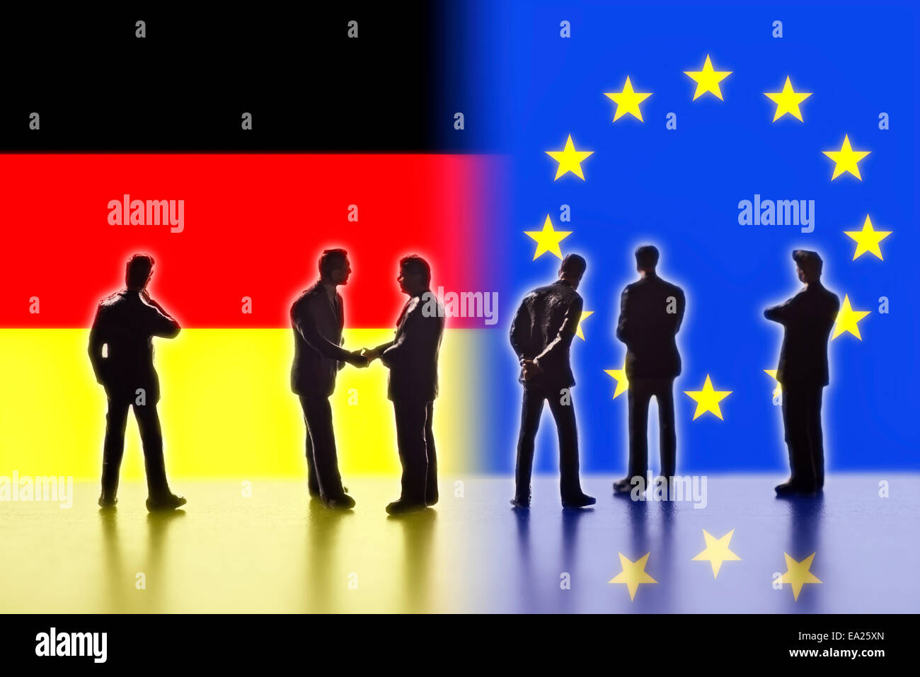 Model figures symbolizing politicians are facing the flags of Europe and Germany. Two of them shake hands. Stock Photo