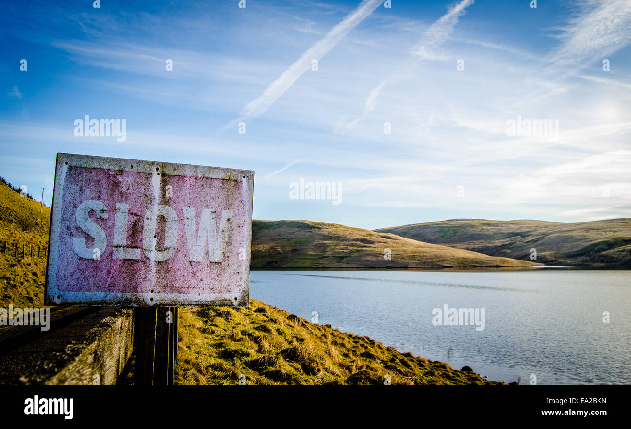 Rustic Slow Sign Beside Tranquil Scenic Lake Stock Photo