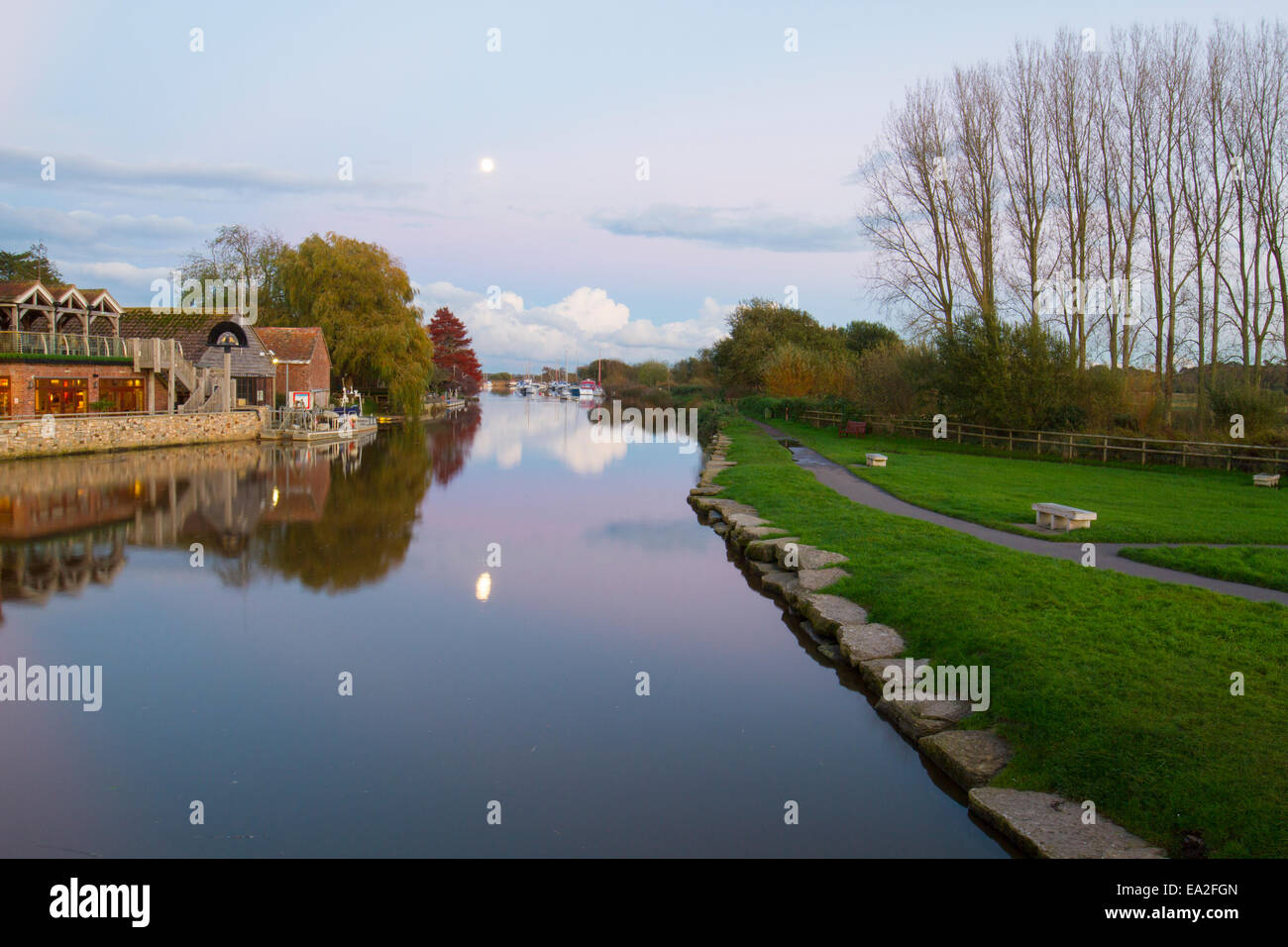 Moon reflecting on river with pink sky and serene sunset Stock Photo