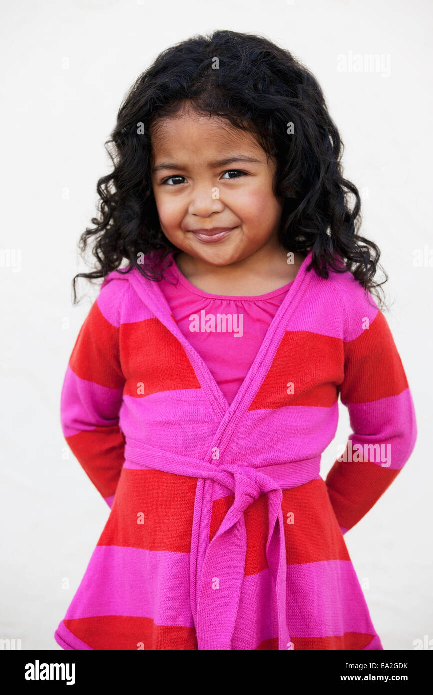A young girl wearing a pink and red striped sweater against a white ...