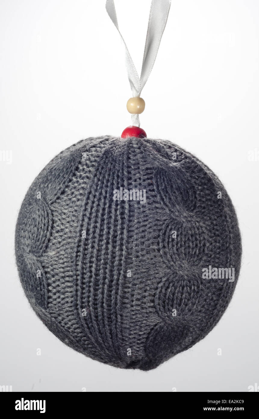 A gray knitted Christmas ball ornament hangs from a white ribbon Stock Photo