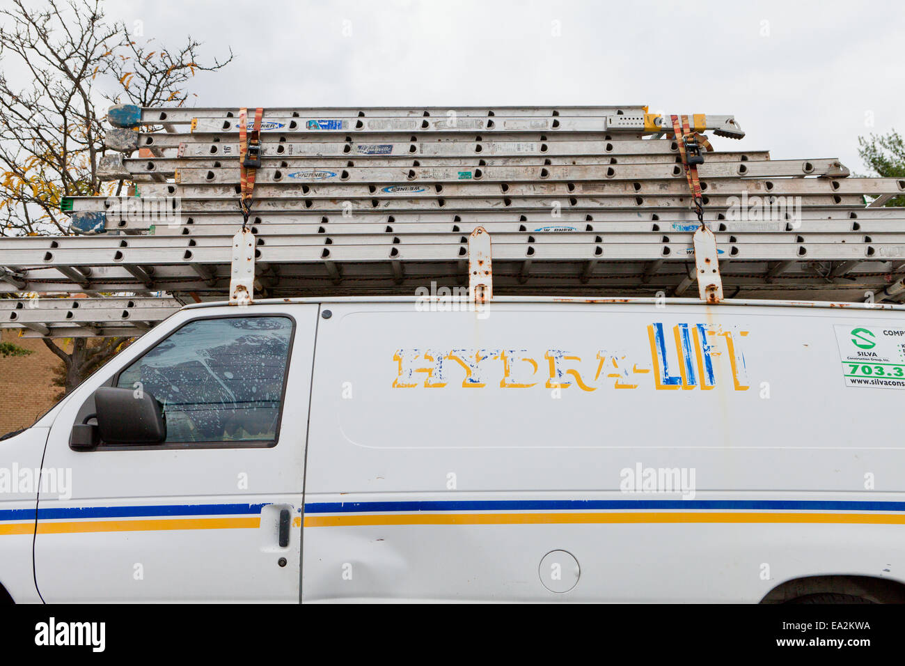 Aluminum ladders stacked atop handyman's service van USA Stock Photo