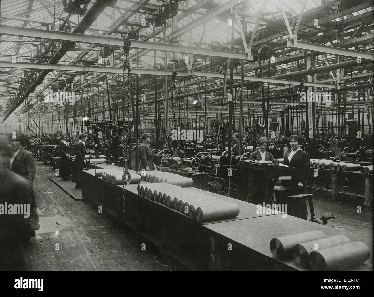 The image shows a woman operating a Sunderland gear planer, a machine used for gear cutting. The machine is an essential tool in mechanical engineering, designed for precision in manufacturing gear components. Stock Photo