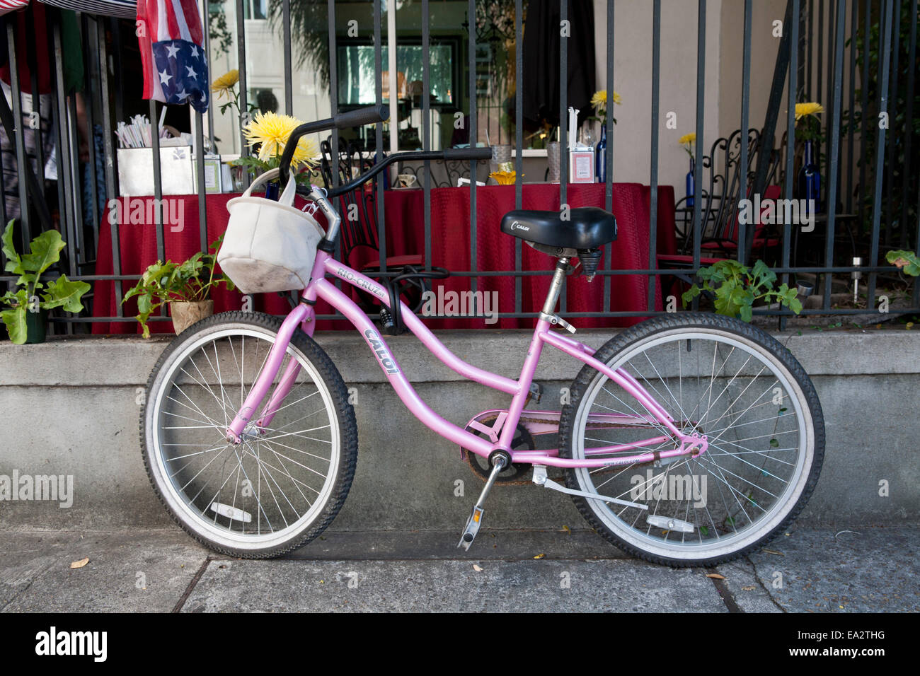 Pink bicycle parked in front of an outdoor restaurant. Stock Photo