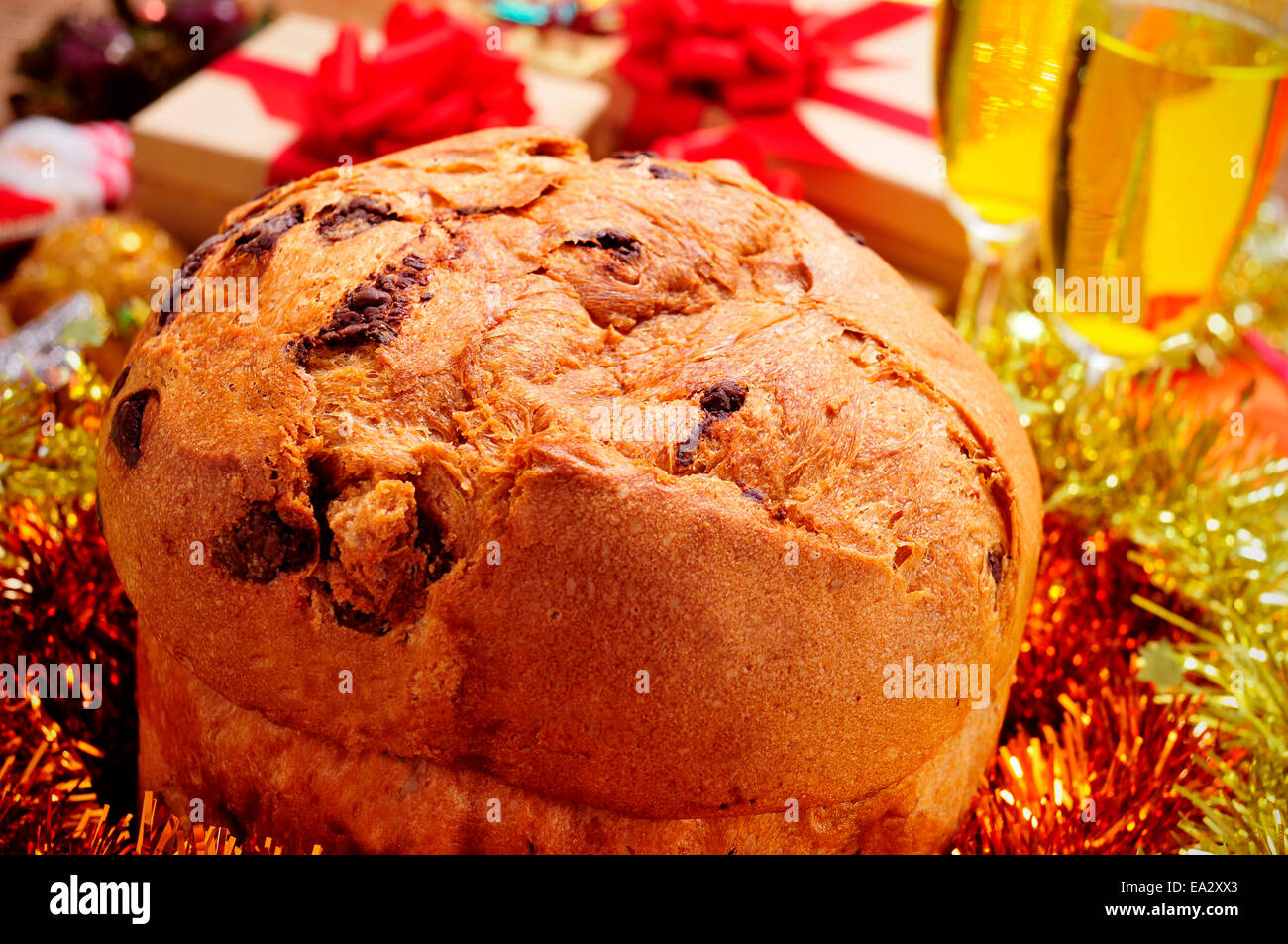 closeup of a panettone, a typical Italian sweet for Christmas time, on a table with champagne and gifts Stock Photo