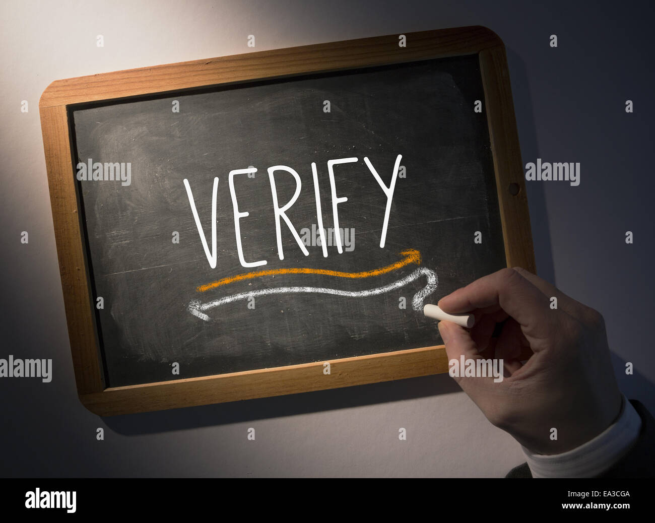 Hand writing Verify on chalkboard Stock Photo