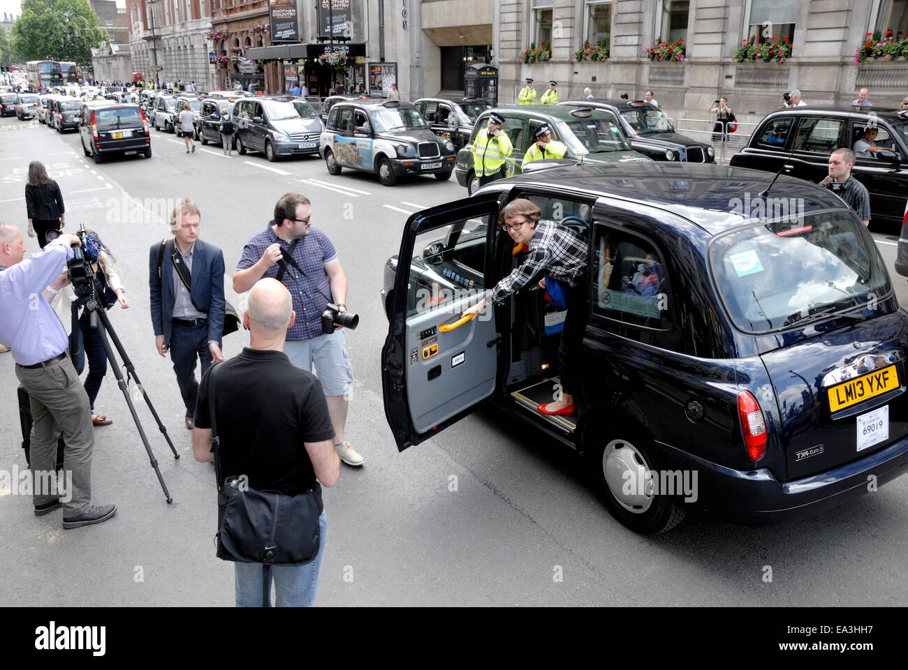 London, England, UK. Woman getting out of a black taxi cab in Whitehall - TV film crew Stock Photo