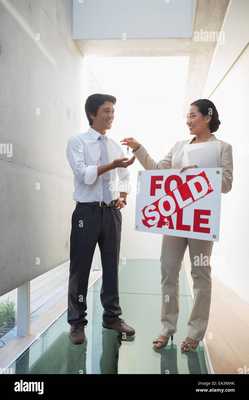 Estate agent giving keys to new home owner Stock Photo - Alamy