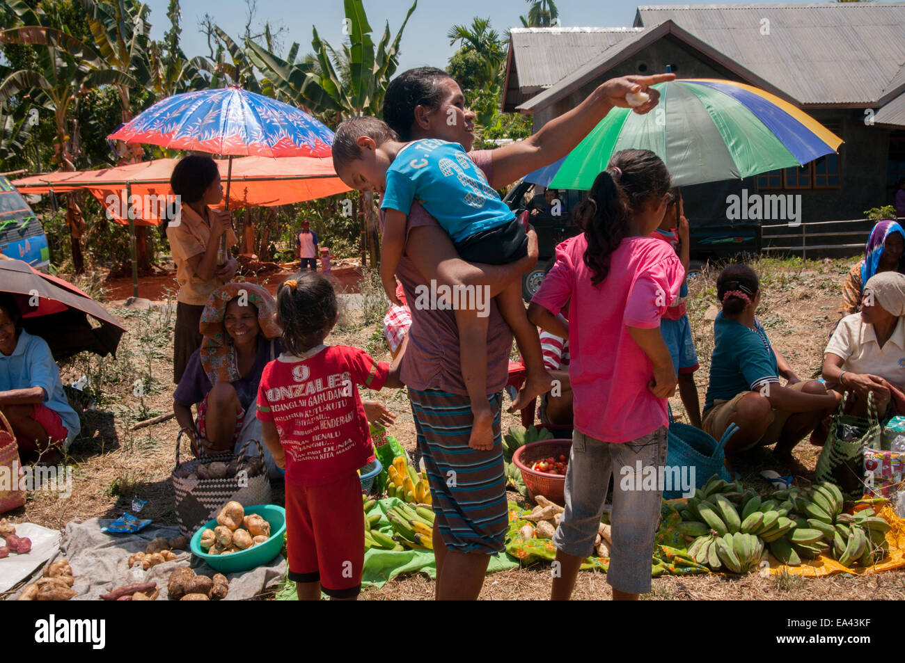 A woman carries her sleeping child at a barter market in Lembata Island, Indonesia. Stock Photo