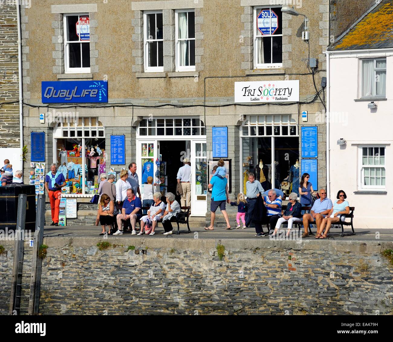 Tourists enjoying the morning sun on the quayside in Padstow Cornwall England uk Stock Photo