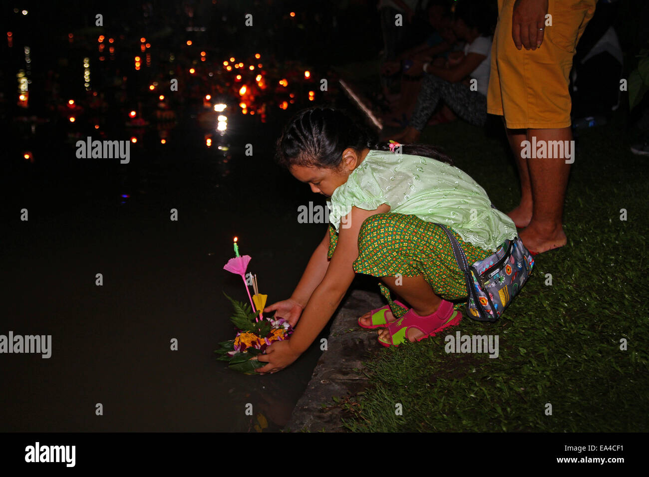 Chatuchak Park's lake, Bangkok, Thailand. 6th November 2014. A little girl places her krathong (small vessel) in the water during Loi Krathong, an annual festival during which people give thanks to the goddess of water (Phra Mae Khongkha) and seek forgiveness for past misdeeds. Credit:  Maria J Atkins/Alamy Live News Stock Photo