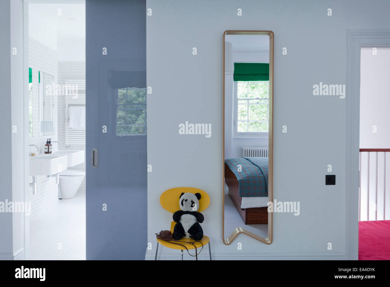Hall mirror with view through sliding door to bathroom in London home
