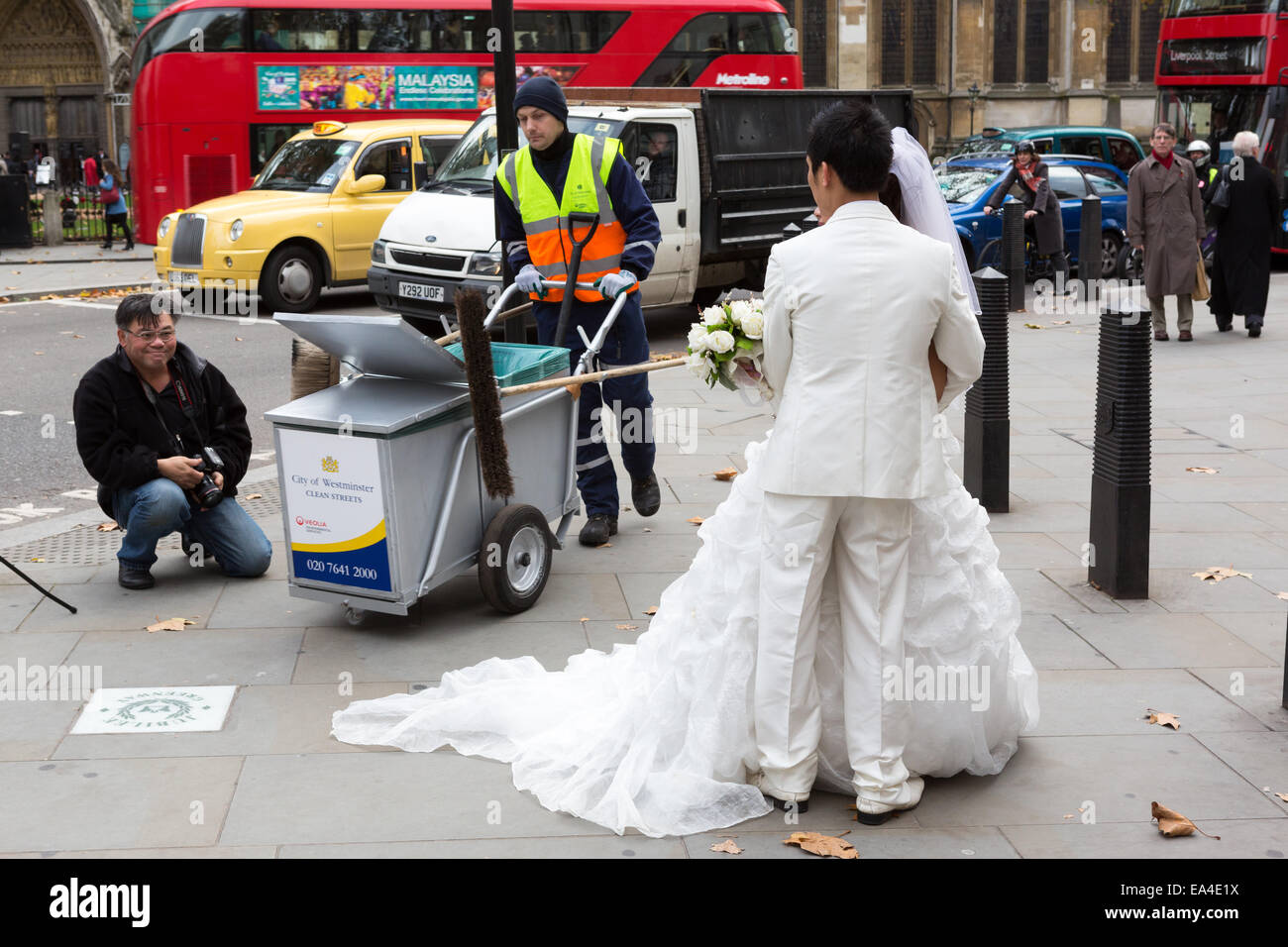 A council street sweeper from Westminster Council walks through a Chinese wedding photo shoot in London Stock Photo