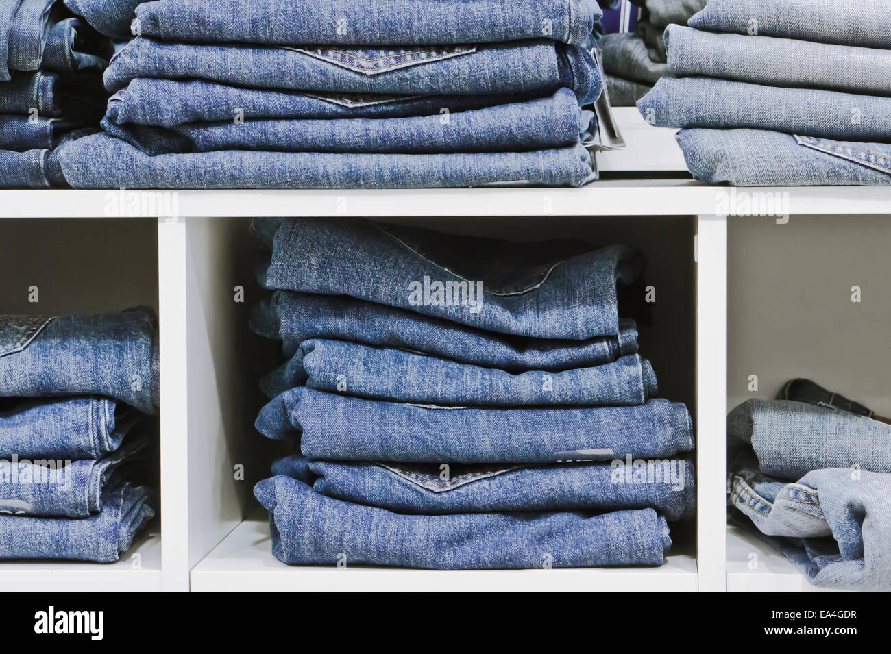 Folded jeans on a shelving unit Stock Photo Alamy