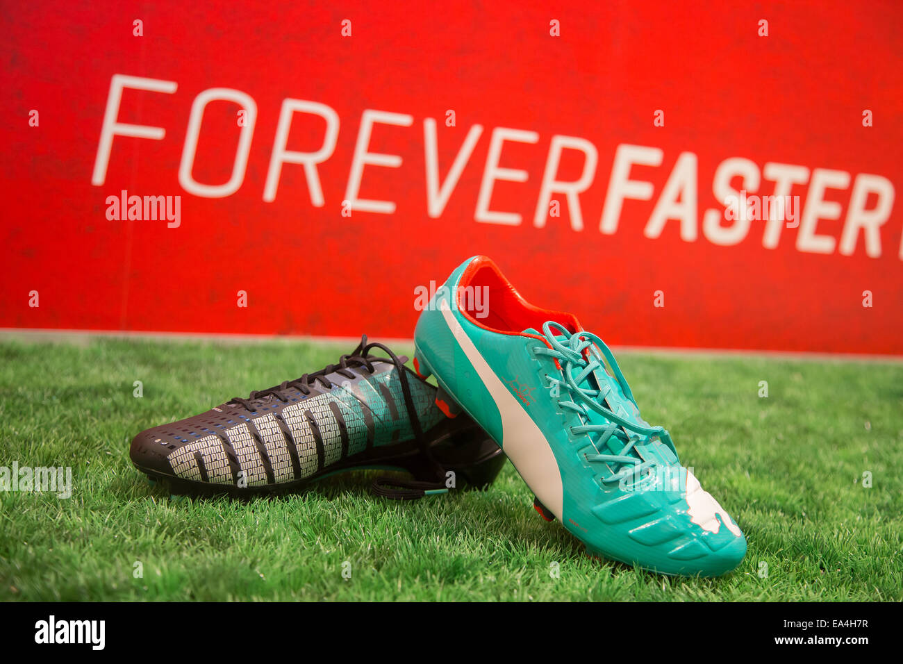 PUMA football boot evoSPEED (l.) and evoPOWER lying on the grass with  Forever Faster slogan in the background. COMMERCIAL HANDOUT/EDITORIAL USE  ONLY/NO SALES. Please quote the source "photo: PUMA/Ralf Roedel Stock Photo  -