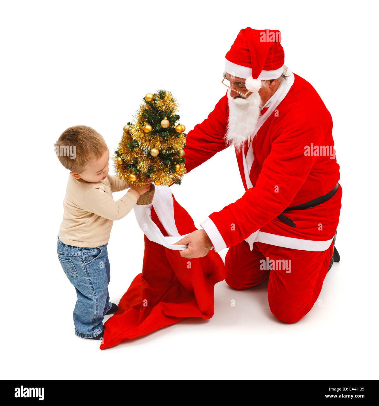 Little boy putting a small, decorated Christmas tree in Santa Claus's