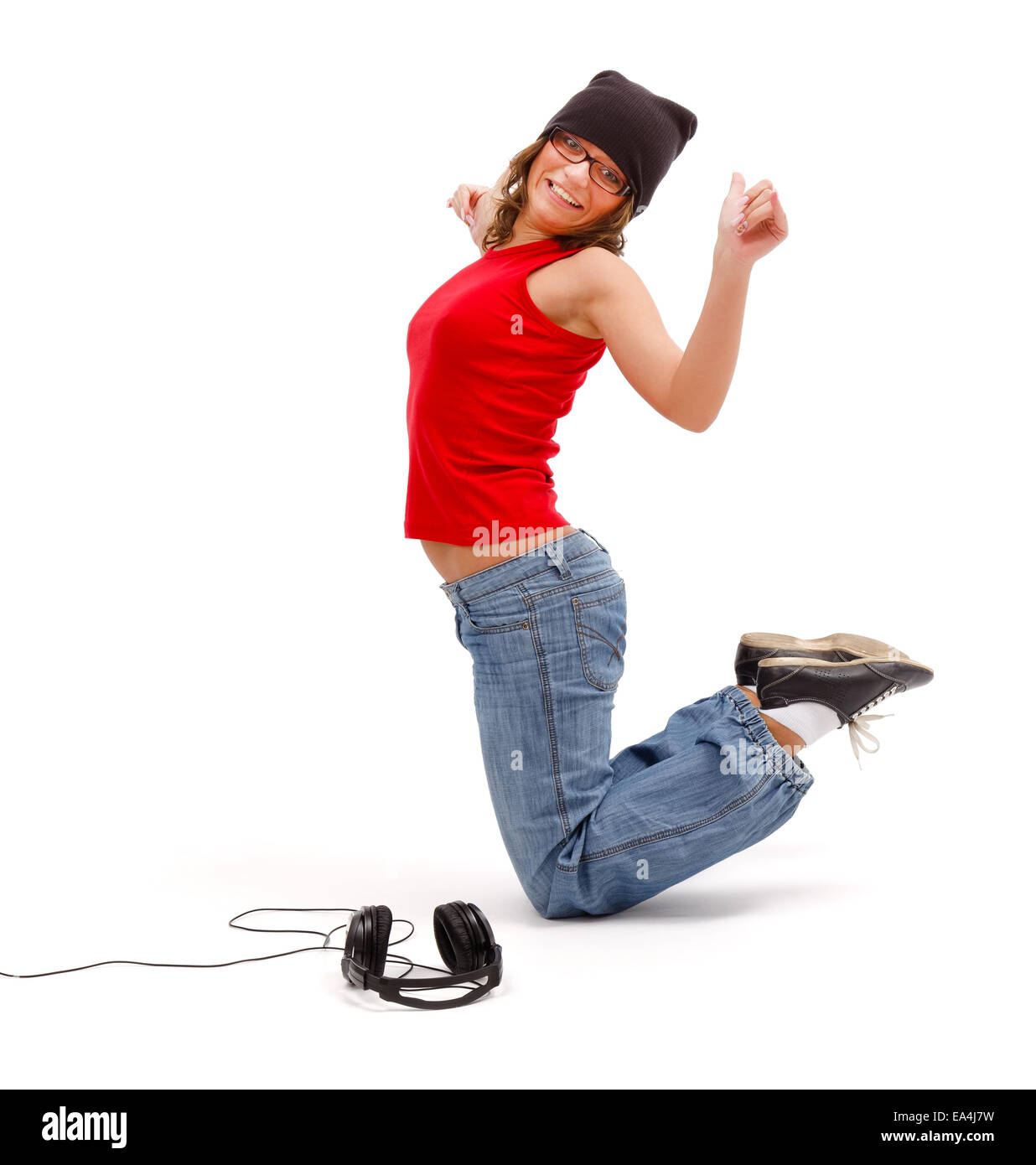 Happy young girl standing on knees while dancing and listening to music Stock Photo