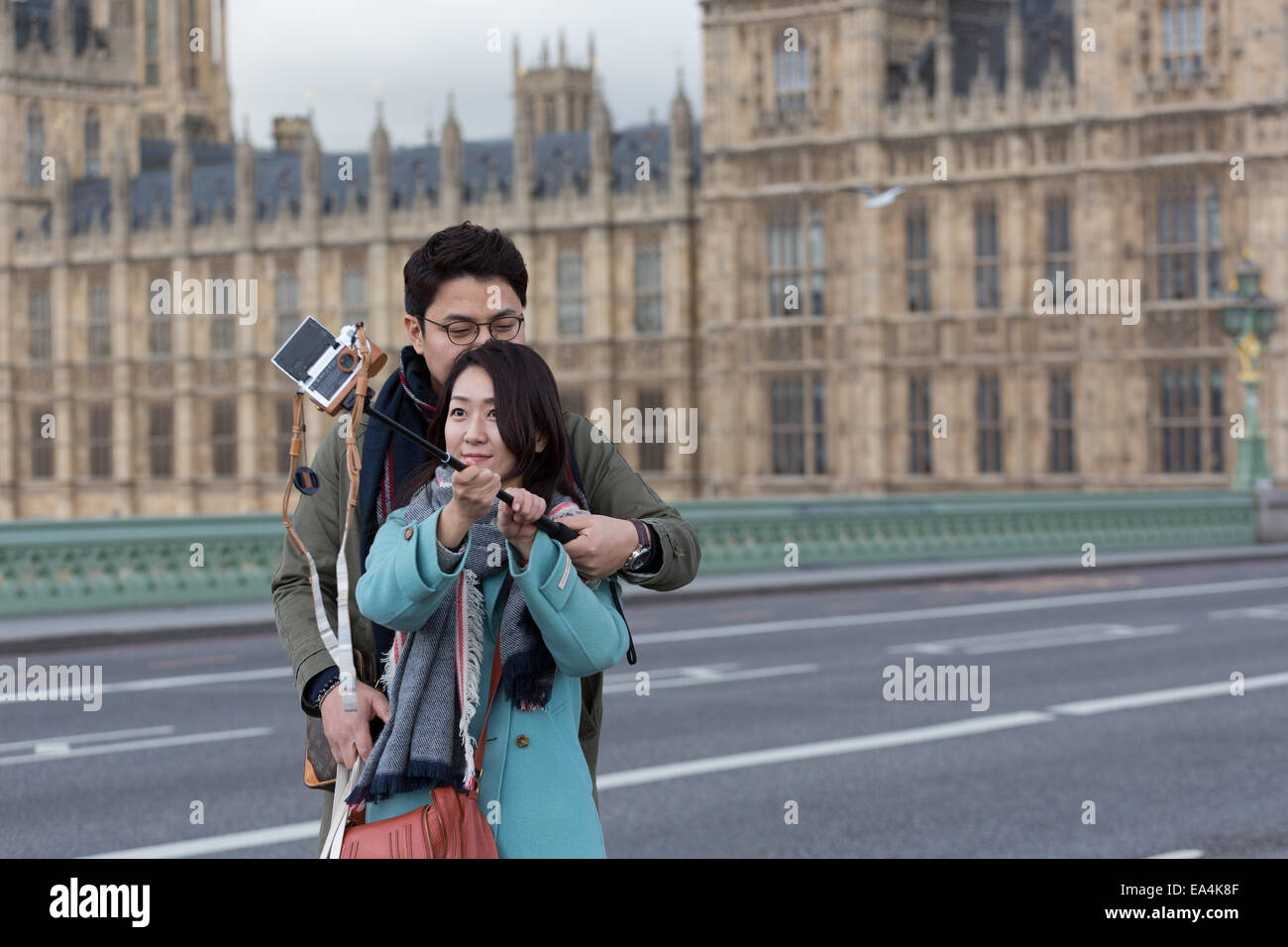 Two Chinese tourists in London capture a selfie photograph using a camera attached to a selfie stick (monopod) Stock Photo