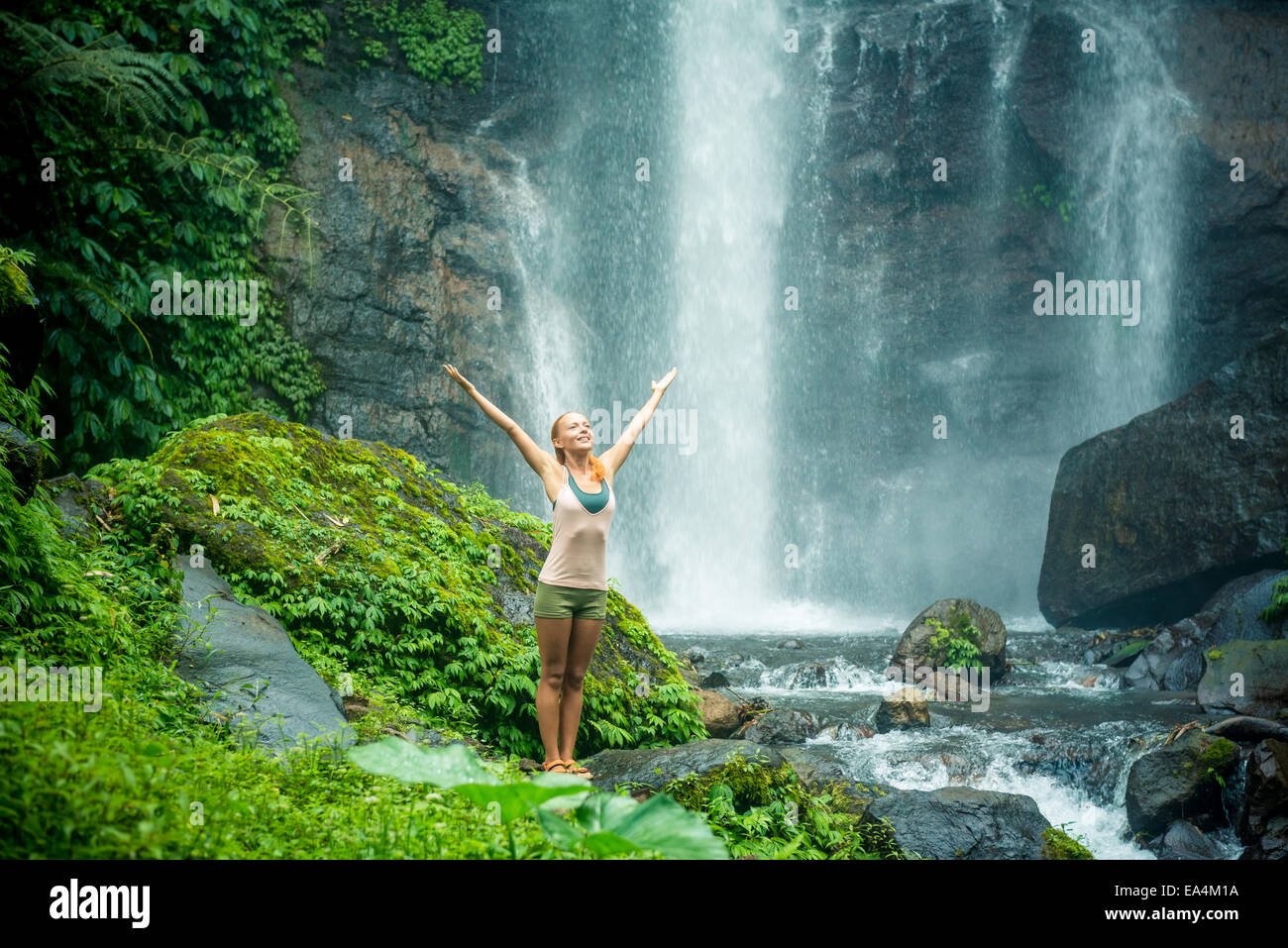 Young woman practicing yoga with waterfall in the background Stock ...