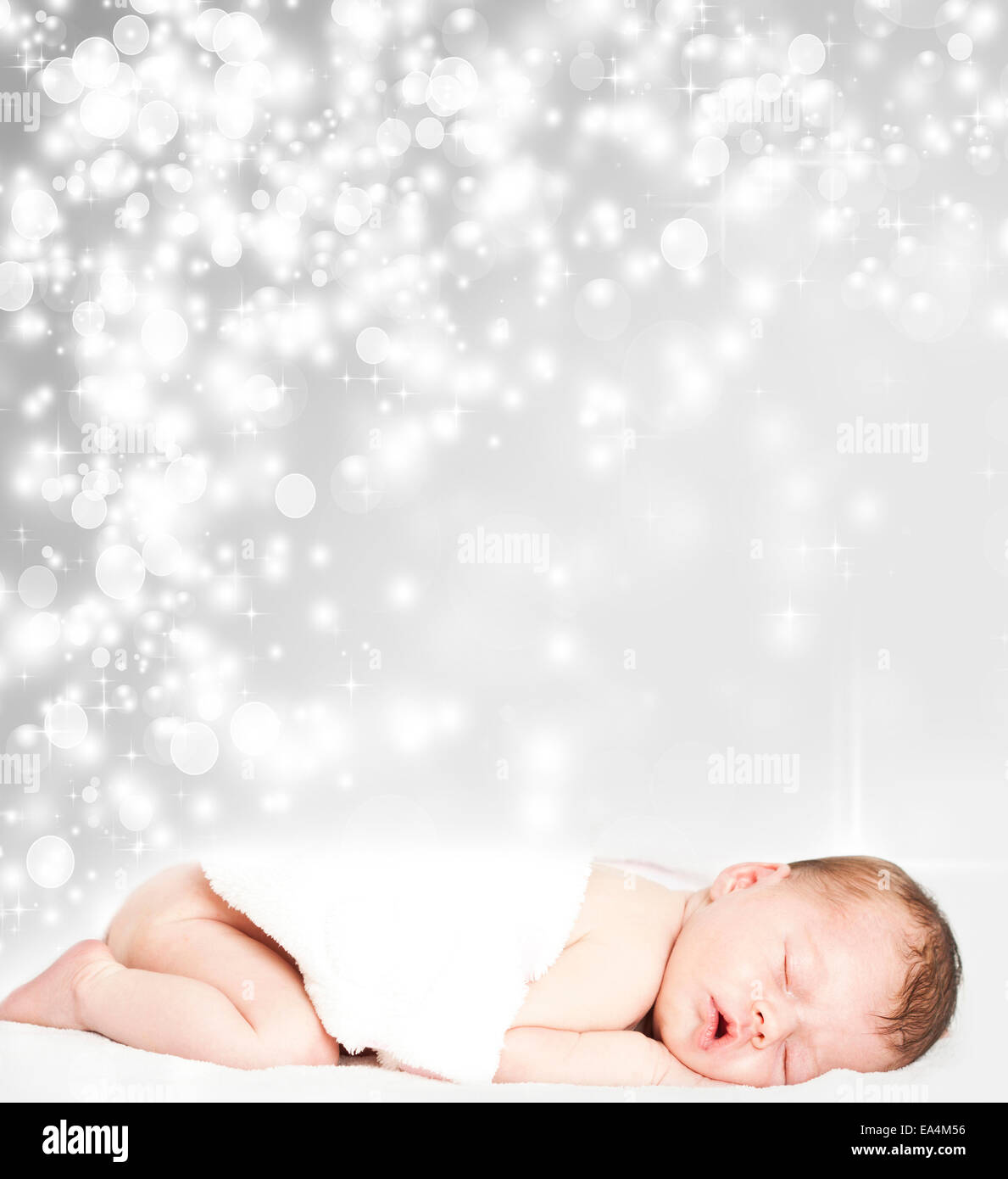 Newborn baby sleeping in front of abstract silver Christmas