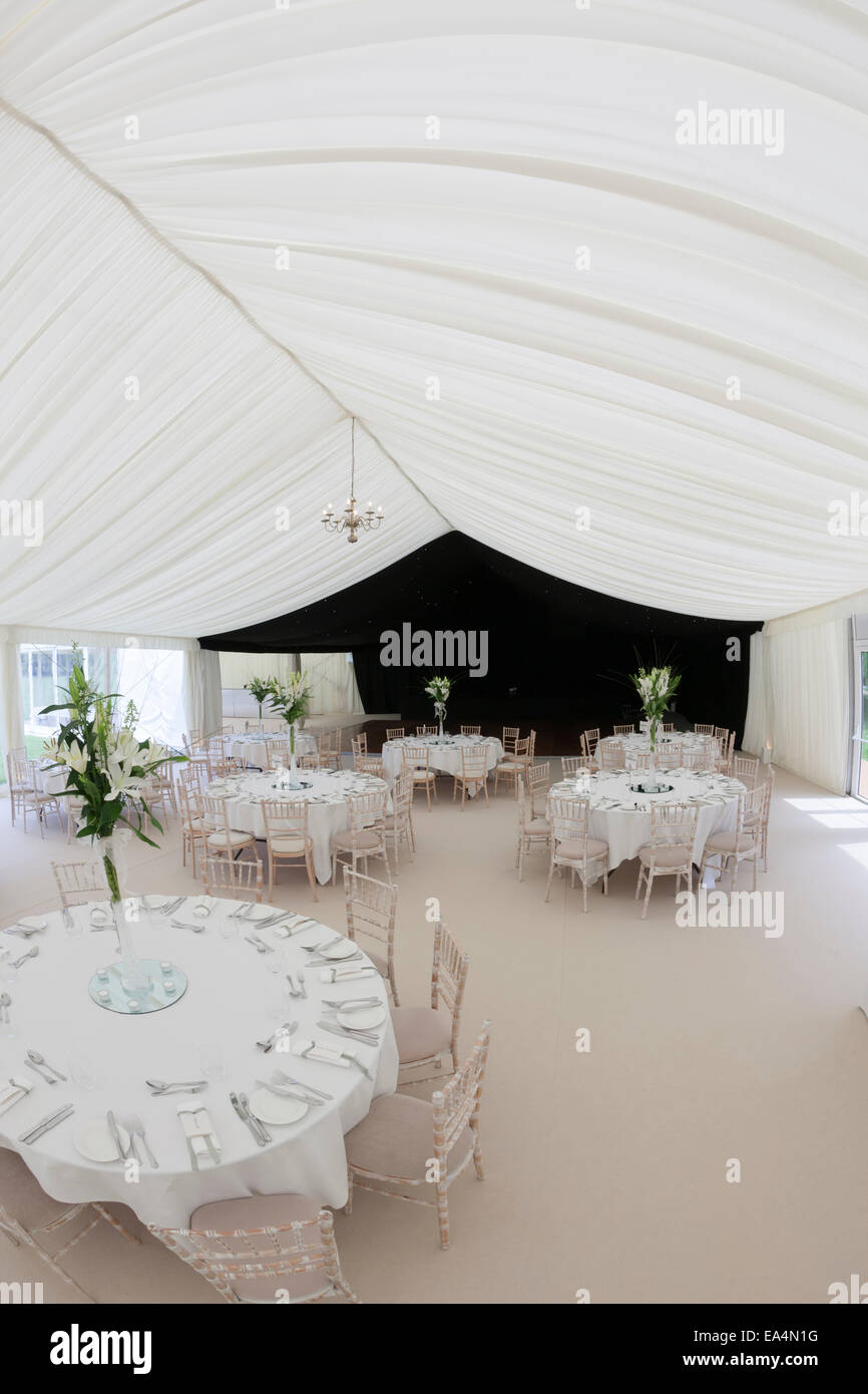 Inside a marquee tent with wedding tables and places set Stock Photo