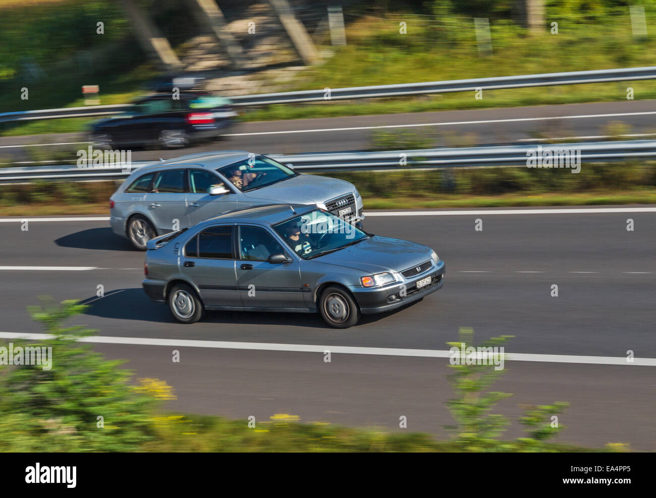 Two cars speeding along a motorway, one overtaking the other. Motion blur used to give a sense of speed. Stock Photo