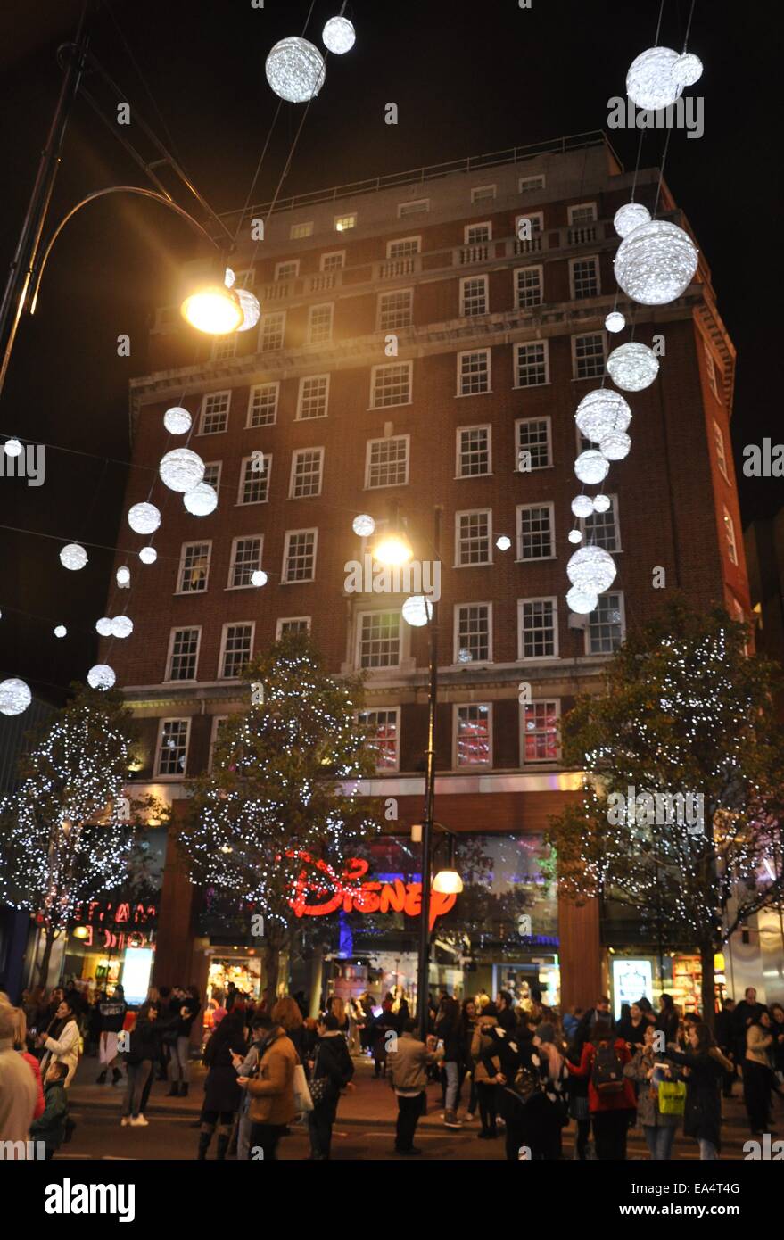 Shoppers Outside Oxford Street Disney Store with Christmas Lights at Night Time, London Stock Photo