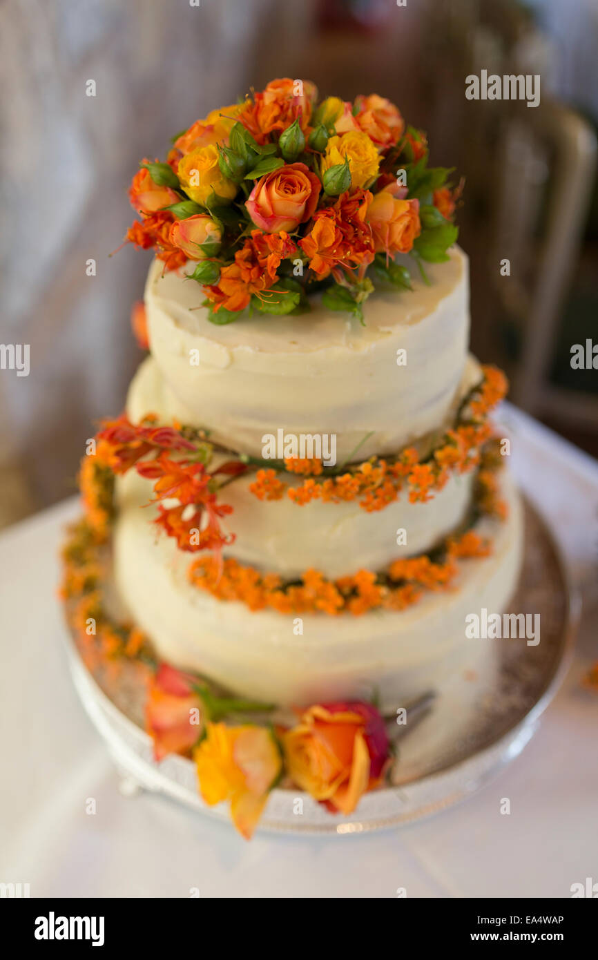 Wedding cake with three tiers and orange flower detail Stock Photo - Alamy