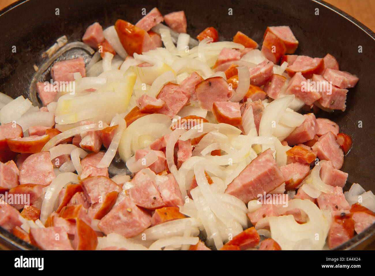 Sliced sausage and onion, on a frying pan, ready to be fried. Stock Photo