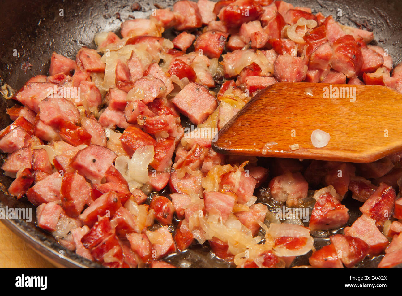 Fired sausage and onion on a frying pan. Stock Photo