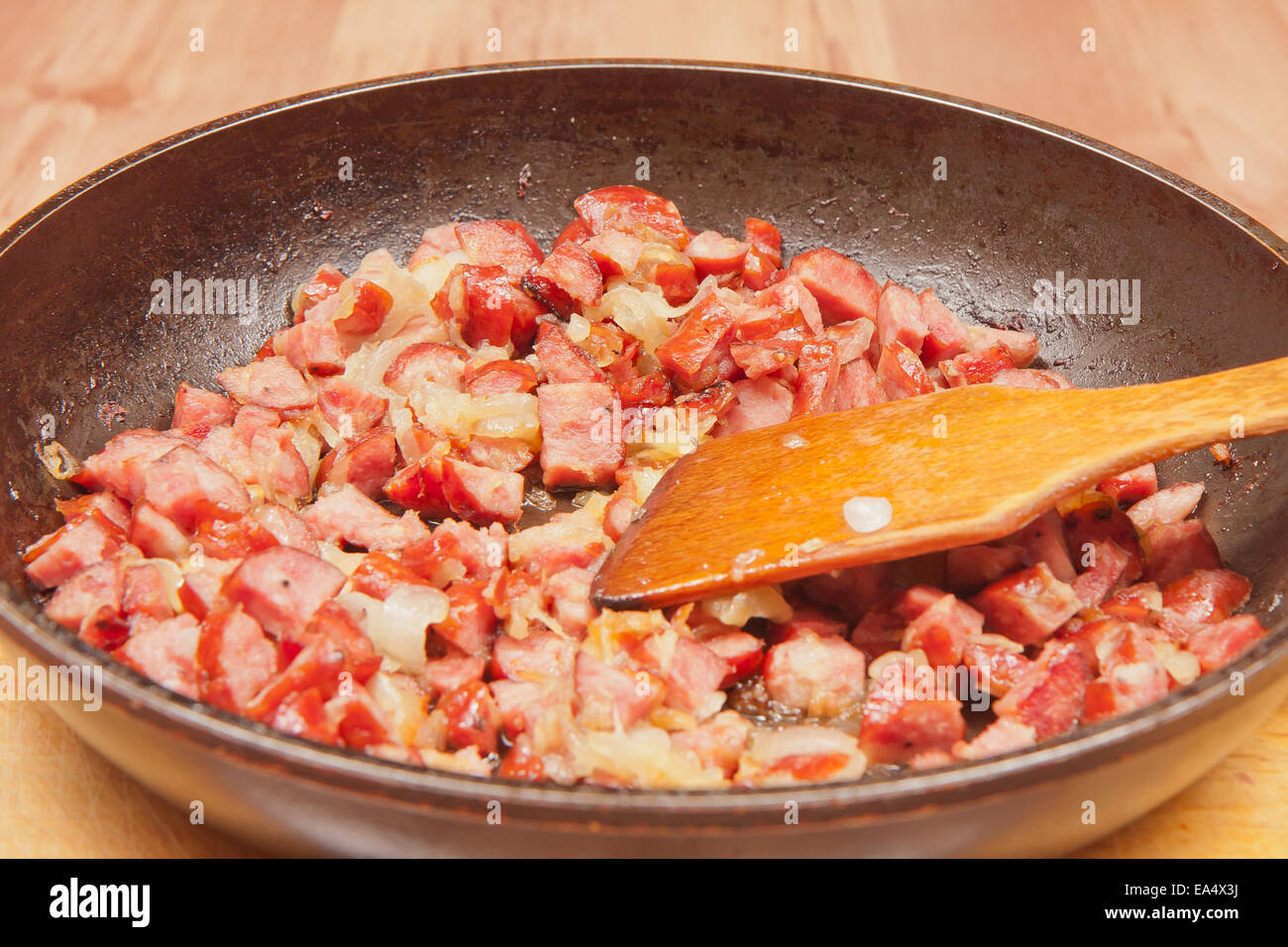 Fired sausage and onion on a frying pan. Stock Photo