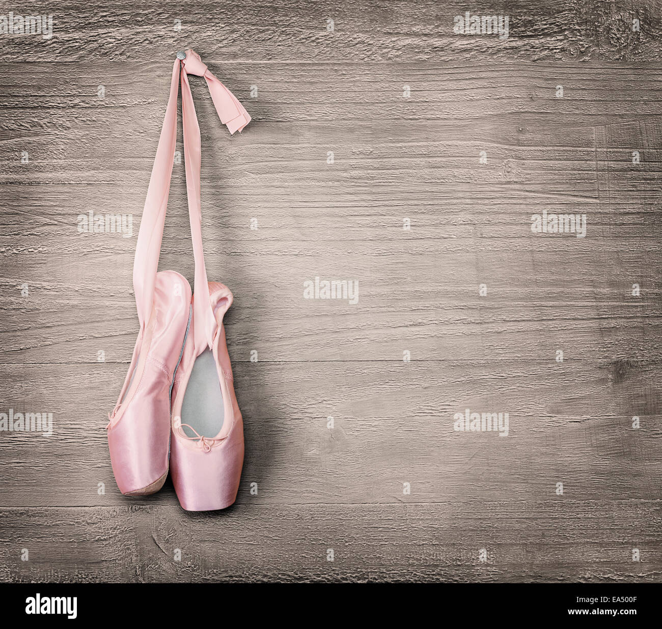 New pink ballet shoes hanging on wooden background.Vintage style. Stock Photo