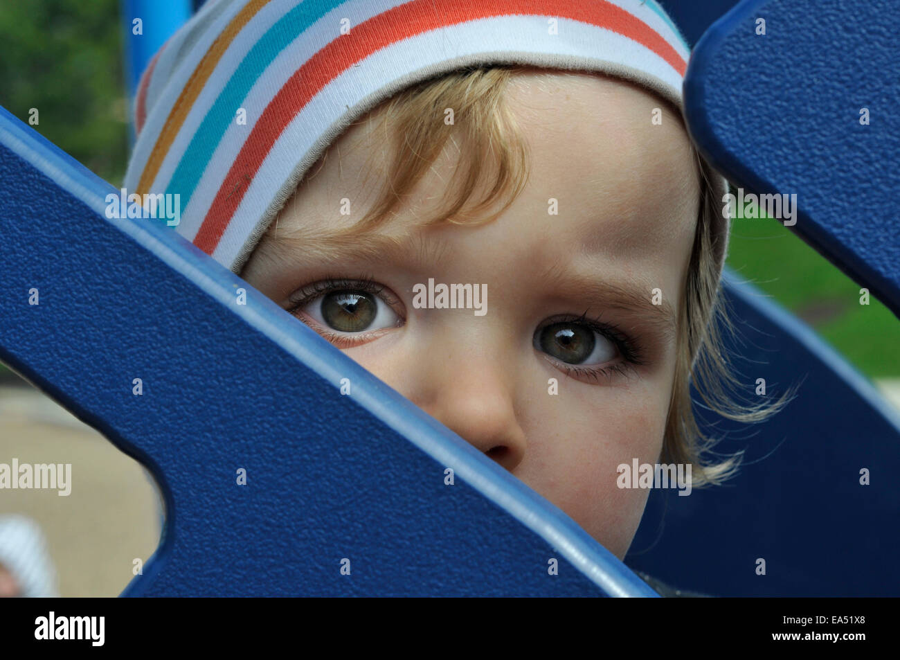 Portrait of a little boy looking through a playground slide Stock Photo