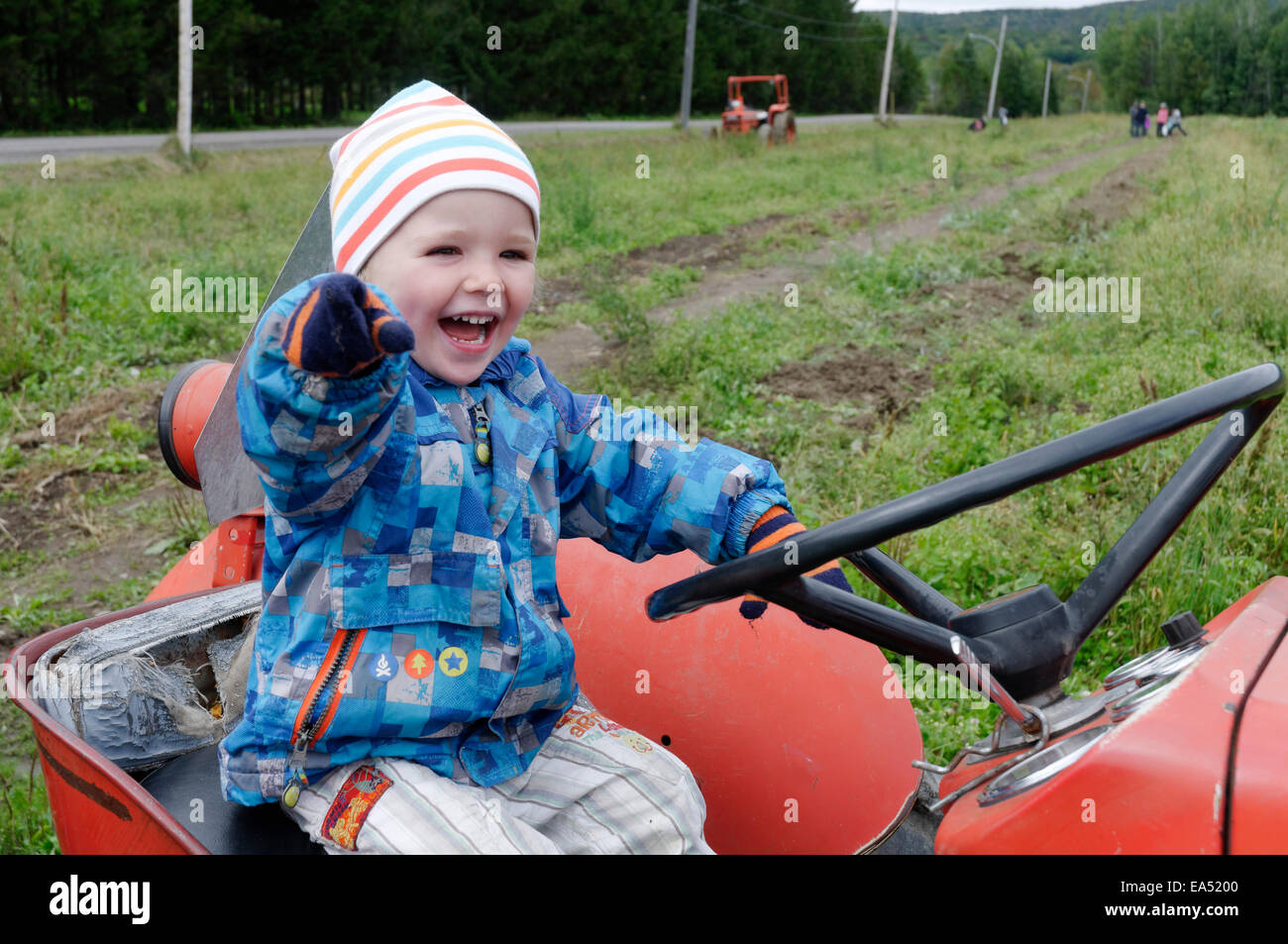 A laughing boy sat on an old Massey Ferguson farm tractor Stock Photo