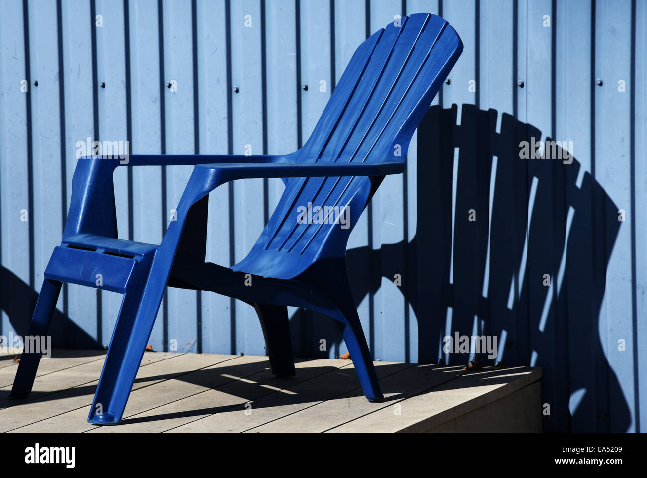 A blue deckchair against a blue wall Stock Photo