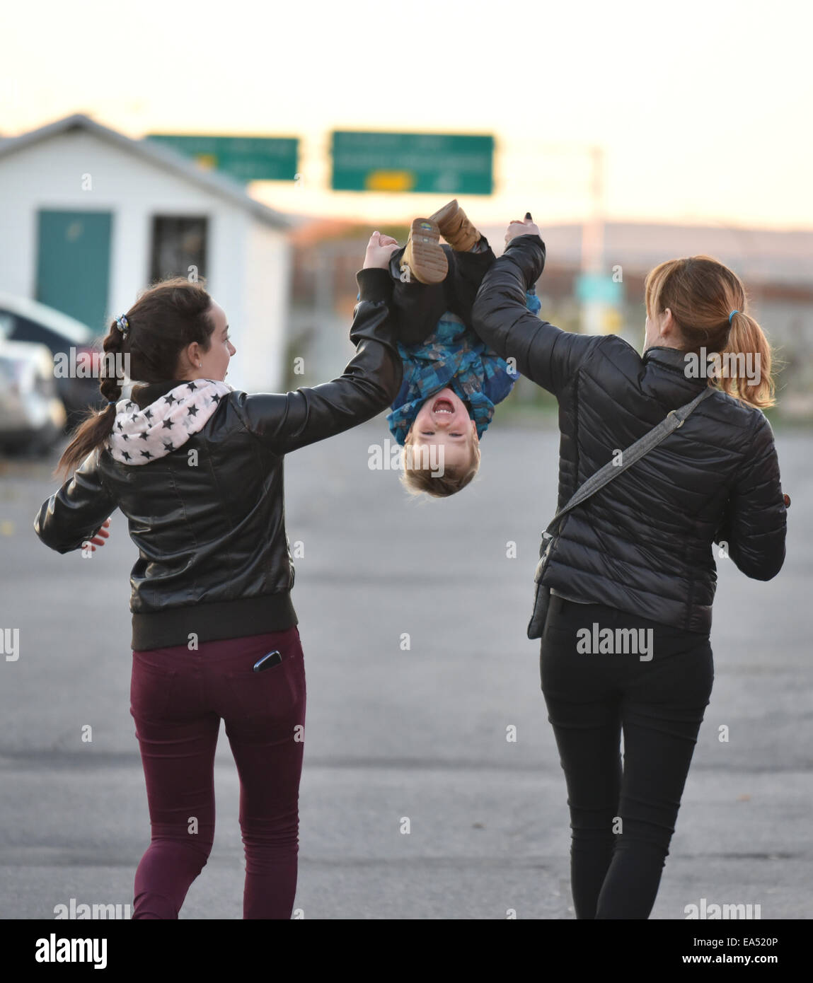A two year old being thrown in the air by two women Stock Photo