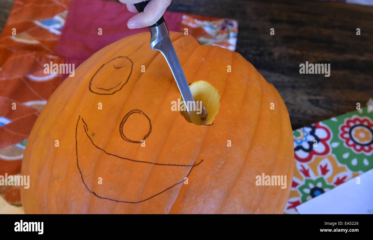 Carving a smiley face into a pumpkin for halloween Stock Photo