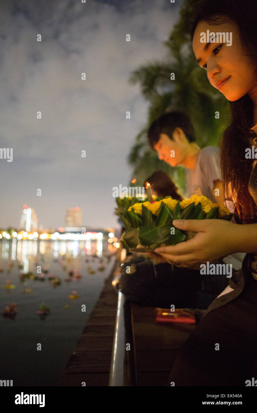Benjakiti Park, Bangkok, Thailand, 6th November 2014. A young Thai woman prepares to float her krathong (decorated basket) on the lake of Benjakiti Park to celebrate the annual Loi Krathong festival. Loi Krathong is an annual festival celebrated in Thailand to give thanks to the Goddess of Water, Phra Mae Khongkha. Credit:  Alison Teale/Alamy Live News Stock Photo