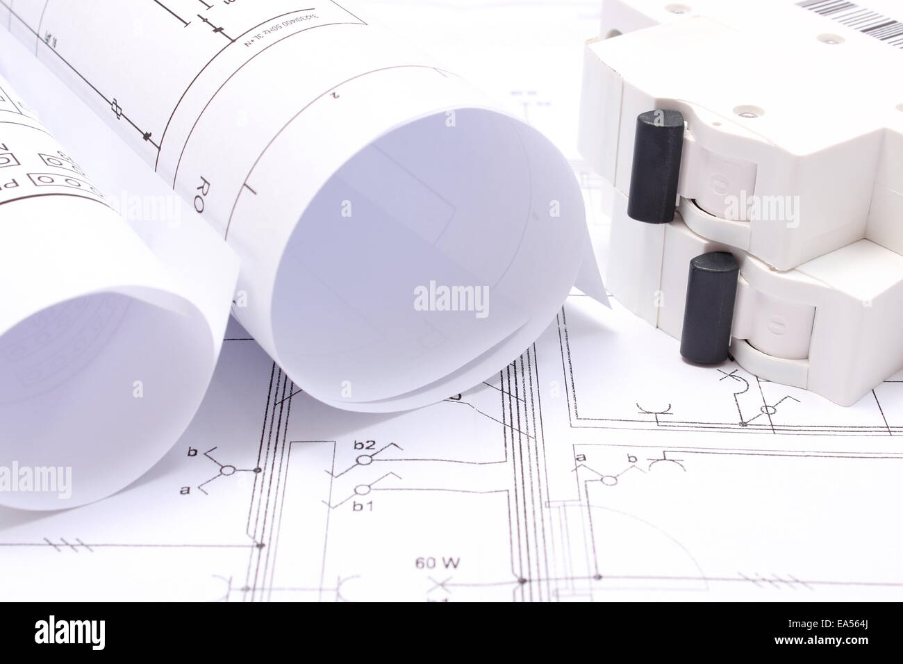 Rolled electrical diagrams and electric fuse lying on construction drawing of house, drawings for the projects engineer jobs Stock Photo