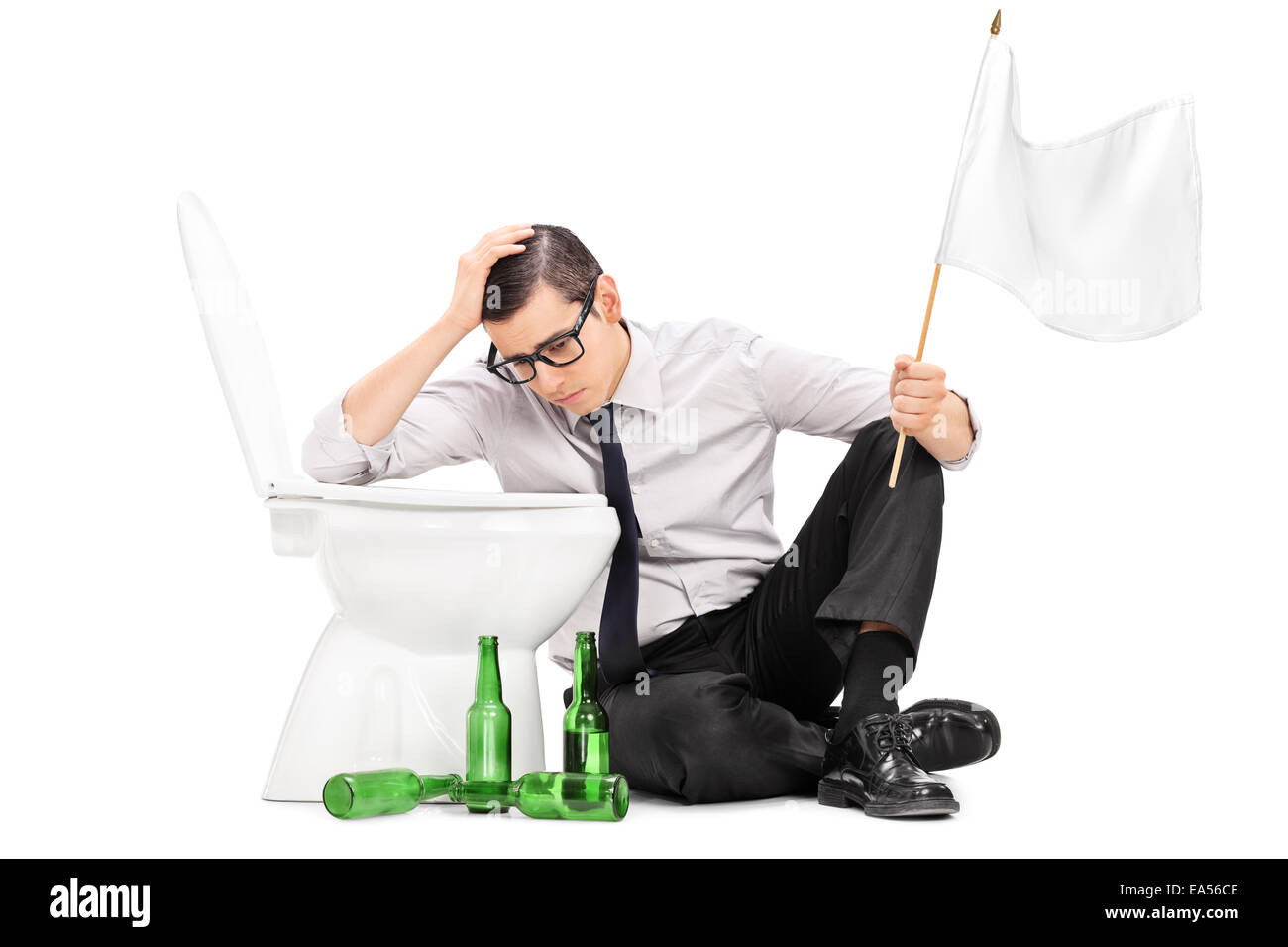Drunk man sitting by a toilet and holding white flag isolated on white background Stock Photo
