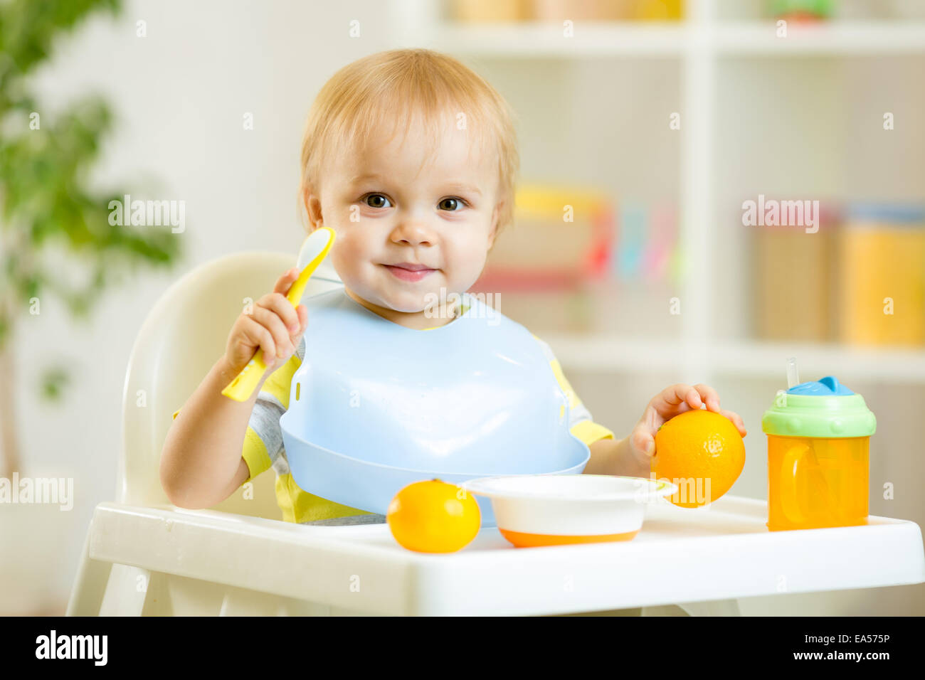 smiling baby child boy eating itself with spoon Stock Photo