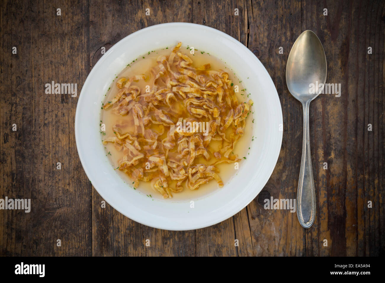 Dish of Swabian Flaedle soup and spoon on dark wood Stock Photo