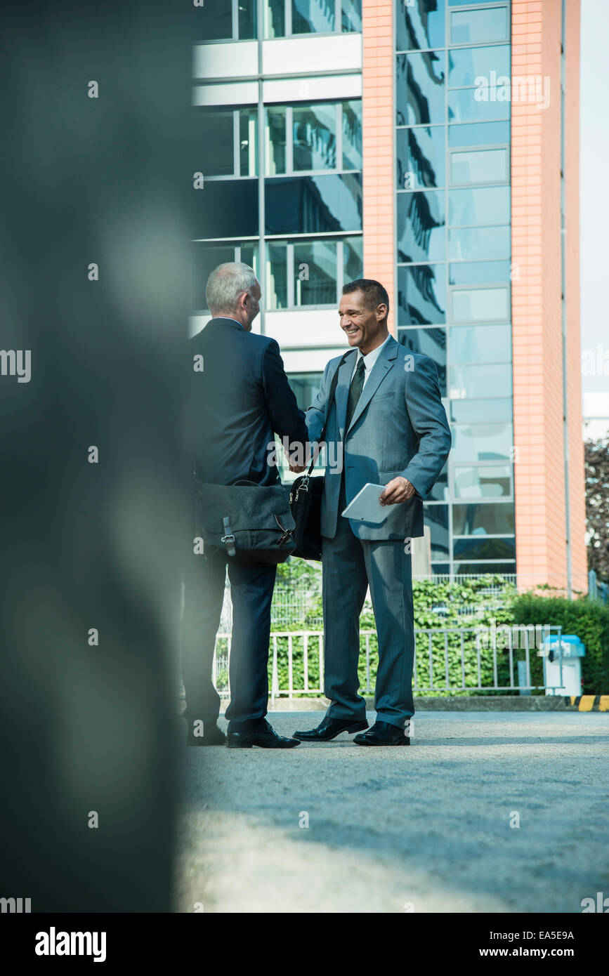 Two businessmen shaking hands outside office building Stock Photo - Alamy