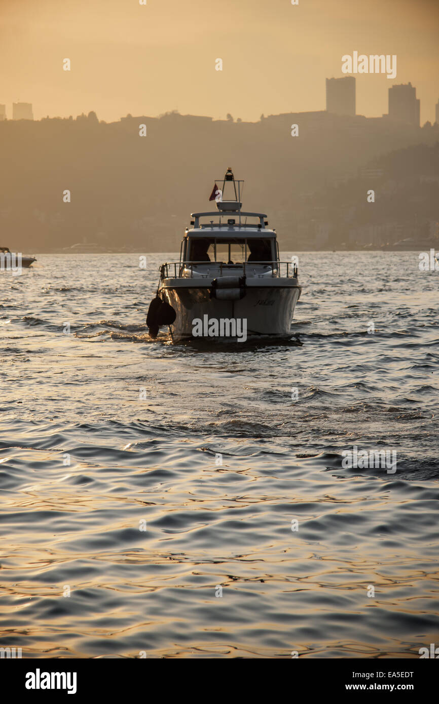 Boat at sunset with reflections on the blue sea Stock Photo - Alamy